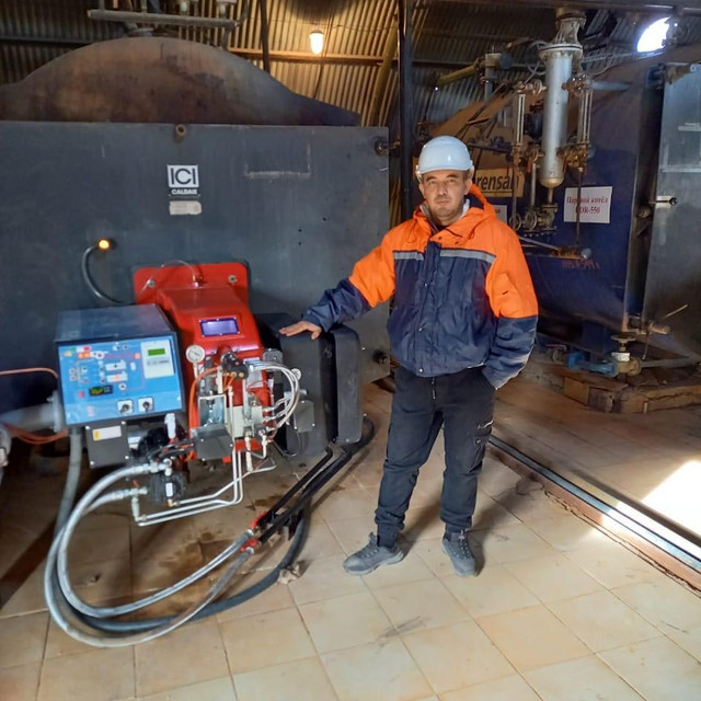 Внутри блочно-модульной котельной Ferroli, работающей на горелках для топочного масло и мазута, со специалистом, стоящим перед большим промышленным котлом